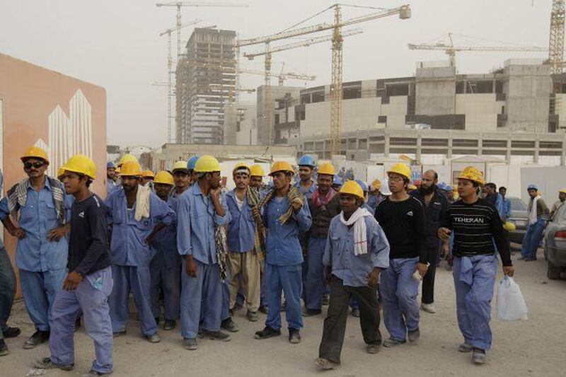 Construction workers wait to board buses at the end of the day from a construction site in Mohammed Bin Zayed City.