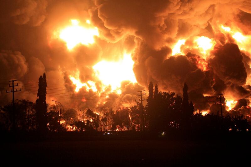 Cars pass by as fire rages through Pertamina Balongan Refinery in Indramayu, West Java, Indonesia, early on Monday, March 29, 2021. Hundreds of people were rescued from a nearby village after the massive fire at the refinery. AP