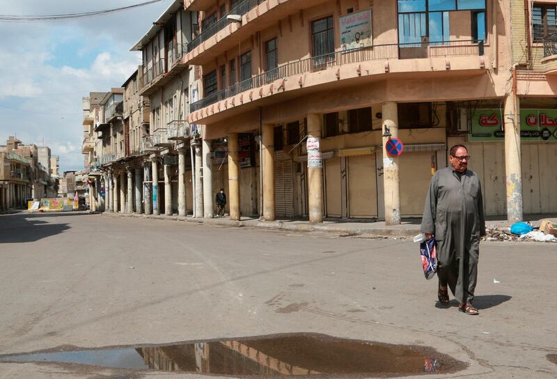 A man walks past closed shops in Baghdad on March 22, 2020. AP Photo