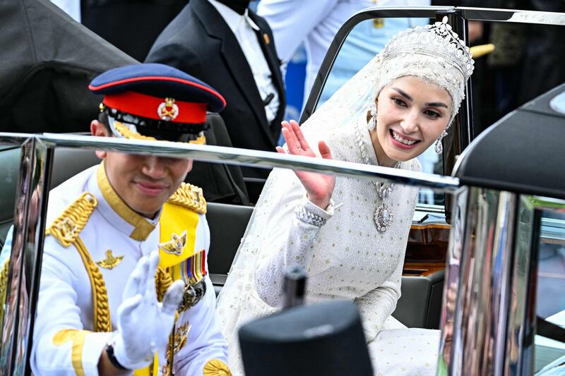 Prince Abdul Mateen and Yang Mulia Anisha Rosnah wave from their car during the wedding procession in Brunei's capital Bandar Seri Begawan on January 14, 2024.  (Photo by MOHD RASFAN  /  AFP)
