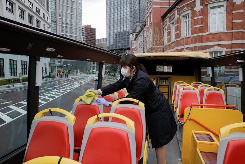 A tour guide for the Hato Bus company disinfects seats on an open-top sightseeing bus. The tour service resumed after Japan's government lifted the Covid-19) state of emergency in the Tokyo area. Reuters