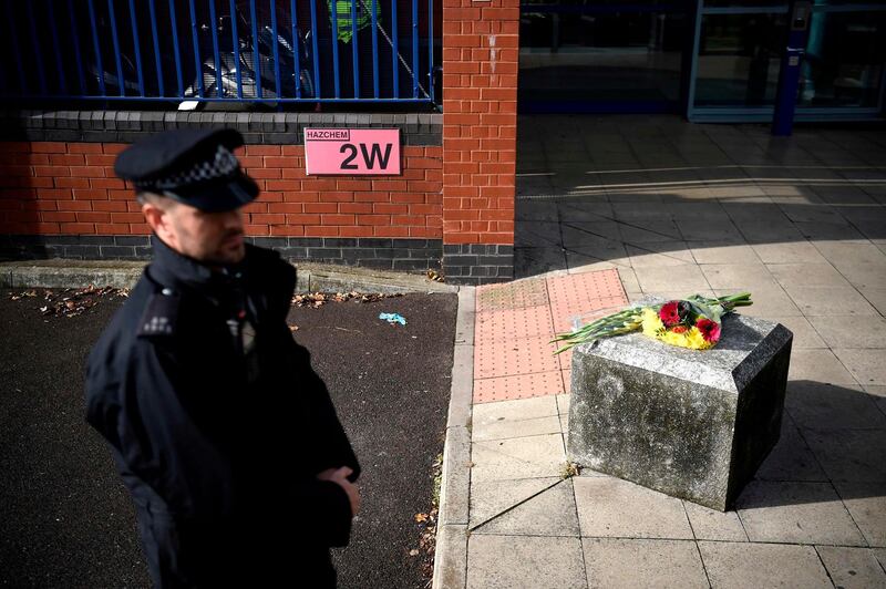 A police officer stands near flowers placed outside the Croydon Custody Centre in south London on September 25, 2020, following the shooting of a British police officer by a 23-year-old man being detained at the centre.  A British police officer was shot dead in the early hours of Friday morning, Scotland Yard said, the first officer to be killed by gunfire while on duty in over eight years. / AFP / DANIEL LEAL-OLIVAS
