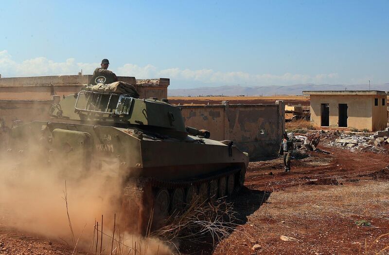 A Syrian government tank drives next to a building near the town of Khan Shaykhun in the southern countryside of the rebel-held Idlib province on August 18, 2019. A Turkish military convoy crossed into jihadist-run northwest Syria on August 19, it's path blocked by advancing regime troops as tensions soared between Damascus and Ankara, which said its forces were targeted by an air strike. / AFP / -
