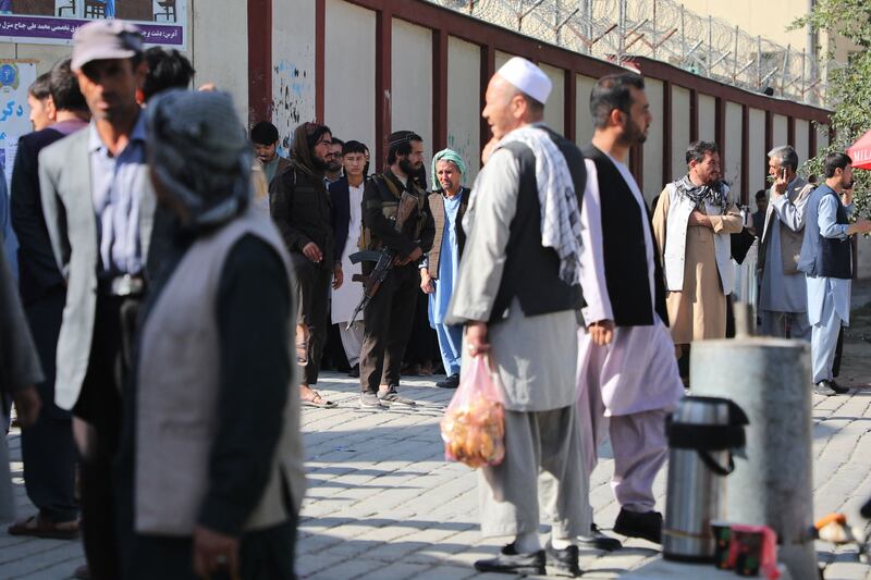 Taliban fighters stand guard outside a hospital in Kabul as people gather to search for relatives.  AFP