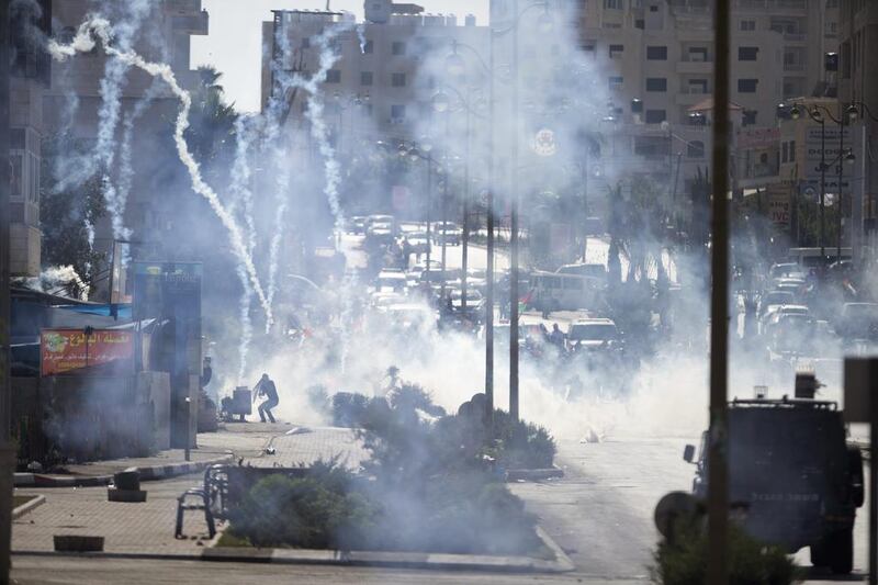 Israeli troops fire tear gas during clashes with Palestinian demonstrators near Ramallah, West Bank, yesterday. Tensions and violence have been mounting in recent weeks. Majdi Mohammed / AP Photo