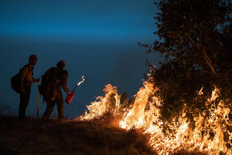 Firefighters light a controlled burn along Nacimiento-Fergusson Road to help contain the Dolan Fire near Big Sur, California. AP Photo