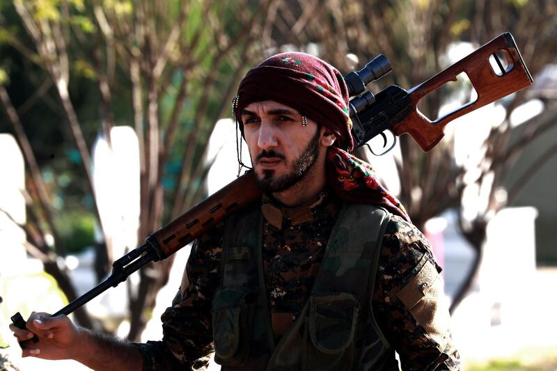 A fighter from the Syrian Democratic Forces (SDF) stands in a cemetary during the funeral a fellow fighter killed in the town of Hajin during battles against the Islamic State (IS) group, in the Kurdish-controlled city of Qamishly in northeastern Syria, on December 3, 2018.  / AFP / Delil SOULEIMAN
