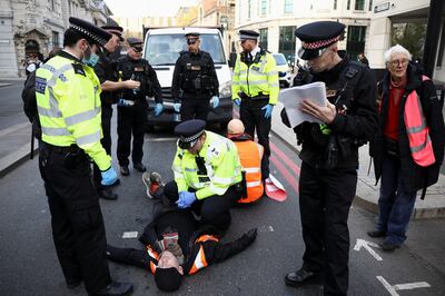 An Insulate Britain activist lies on a road next to police officers during a protest in London. Reuters.