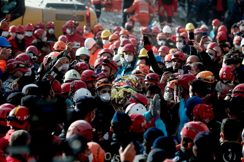 Members of rescue services watch and take photographs with their mobile phones, as colleagues and medics carry 4-year-old Ayda Gezgin, covered in a thermal blanket, after she was rescued in the debris of her collapsed building in Izmir, Turkey, Tuesday, Nov. 3, 2020. Rescuers in the Turkish coastal city pulled Gezgin out alive from the rubble, four days after a strong earthquake hit Turkey and Greece. (Samet Dogru/IHA via AP)