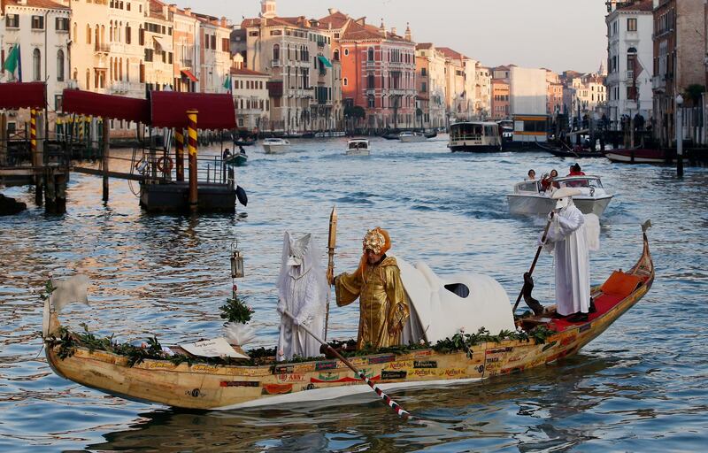 Masked people stand on a gondola as part of the Carnival in Venice, Italy, Saturday, Feb. 16, 2019. The Venice carnival in the historical lagoon city attracts people from around the world. (AP Photo/Antonio Calanni)