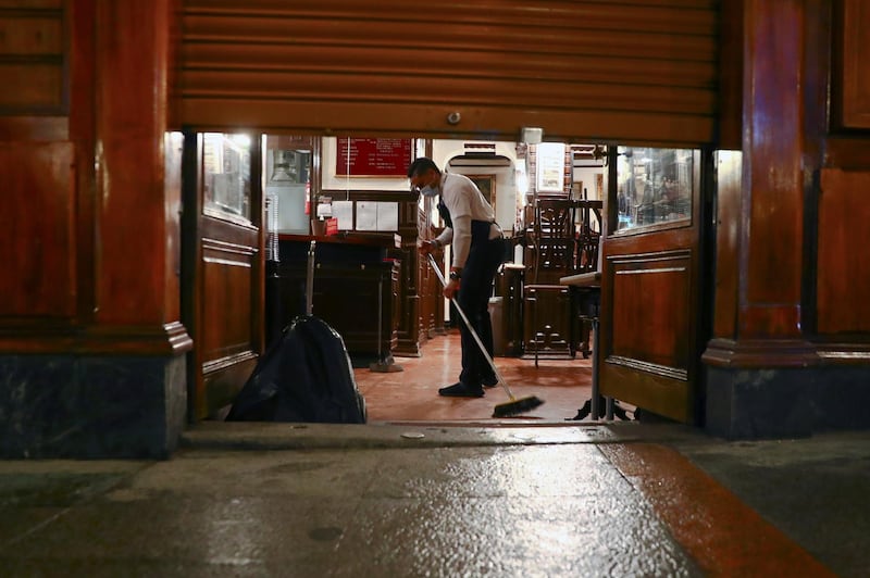 A worker sweeps the floor of a restaurant which is closing due to a curfew in Madrid, Spain. Reuters