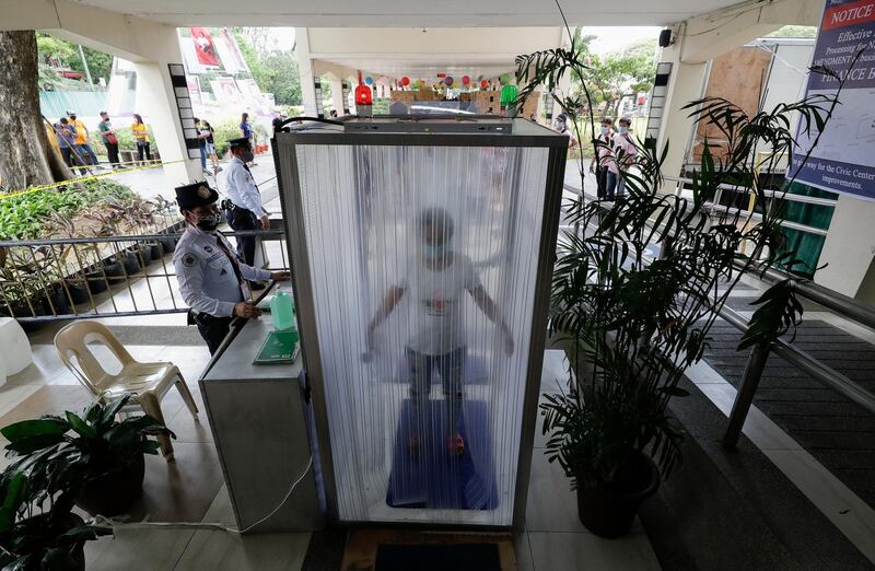 Volunteers and government workers are disinfected inside a cubicle before they enter a local city hall in Metro Manila. AP Photo