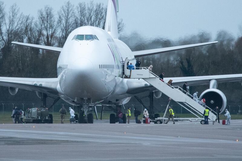 BRIZE NORTON, ENGLAND - FEBRUARY 9: People in protective suits assist passengers as they disembark from a plane, carrying 150 Britons who were trapped in Wuhan following a Coronavirus outbreak, after landing at RAF Brize Norton from China on February 9, 2020 in Brize Norton, England. British citizens who arrived from Wuhan on two previous repatriation flights from Wuhan are quarantined at Arrowe Park Hospital on the Wirral. Coronavirus started in Wuhan in the Hubei Province of China and has spread to two dozen countries worldwide with three confirmed cases in the UK.  (Photo by Leon Neal/Getty Images)