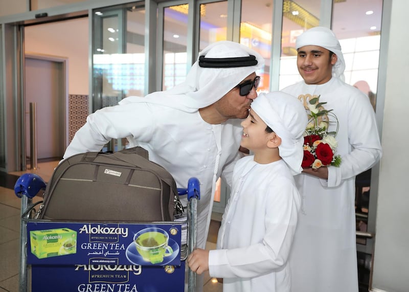 Abu Dhabi, United Arab Emirates - August 15, 2019: Hamdan 15 and Rakan 9 greet their father Mohammed from the Hajj pilgrimage. The pilgrims will be returning following the Eid Al Adha holiday. Thursday the 15th of August 2019. Abu Dhabi International Airport, Abu Dhabi. Chris Whiteoak / The National