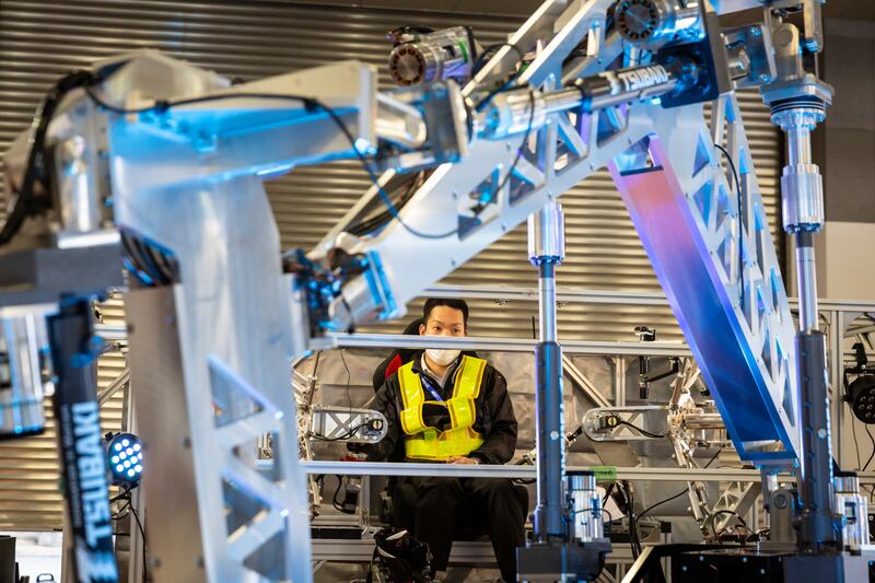 An employee operates an industrial robot in an exhibit showcasing robotic technology related to AI and ICT from Japan and around the globe. Getty Images