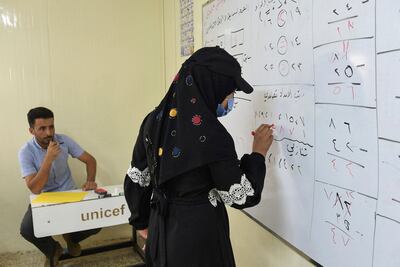 A woman writes on a board at the Al Jadaa facility, south of Mosul in northern Iraq. AFP