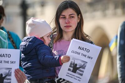 A woman holds a baby with a banner saying "NATO close the sky" during a protest organised by the Ukrainian diaspora asking for NATO intervention on the Russian invasion of Ukraine at Krakow's UNESCO main Square on March 22, 2022. Getty Images