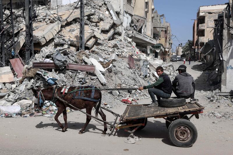 Palestinian boys ride a donkey-pulled cart near a building destroyed in an Israeli bombardment in Rafah in the south of the Gaza Strip. AFP