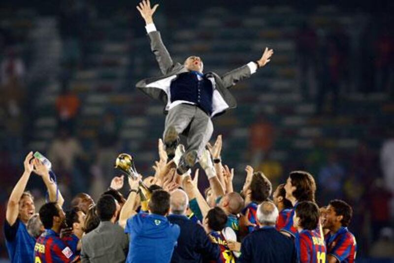 Barcelona players throw coach Pep Guardiola in the air to celebrate the Club World Cup here in Abu Dhabi last year.