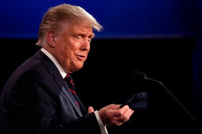 US President Donald Trump looks at his mask as he speaks with Democratic Presidential candidate and former US Vice President Joe Biden during the first presidential debate at Case Western Reserve University and Cleveland Clinic in Cleveland, Ohio, on September 29, 2020.  US President Donald Trump, 74, was forced off the campaign trail on October 2, 2020, after testing positive for Covid-19. Trump announced on Twitter that he and First Lady Melania Trump, 50, had tested positive and were going into quarantine. / AFP / JIM WATSON
