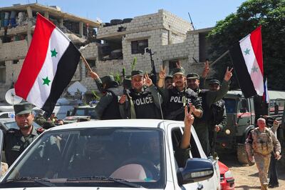 This photo released Saturday, April 14, 2018, by the Syrian official news agency SANA, shows Syrian police units waving their national flag and giving the victory sign, as they enter the town of Douma, the site of a suspected chemical weapons attack and the last rebel-held town in the eastern Ghouta, near Damascus, Syria. Syrian state TV is broadcasting the deployment of 5,000 policemen and internal security in Douma where an alleged chemical attack last weekend triggered an unprecedented joint US, British, French strikes in Syria. (SANA via AP)