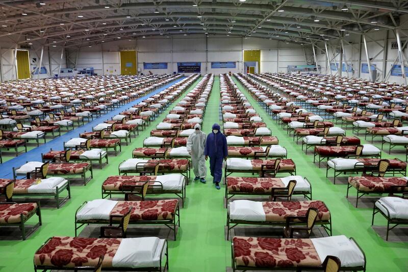 People in protective clothing walk past rows of beds at a temporary 2,000-bed hospital for COVID-19 coronavirus patients set up by the Iranian army at the international exhibition center in northern Tehran, Iran. AP Photo
