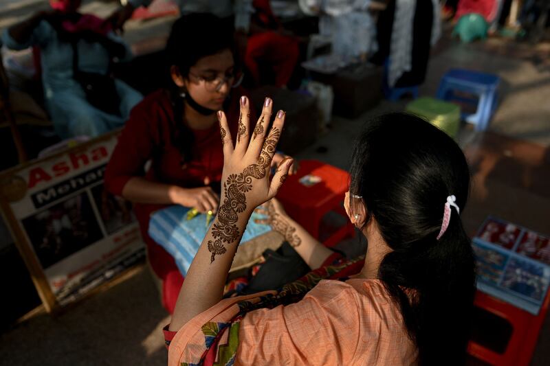 Women have their hands decorated with henna in New Delhi. AFP