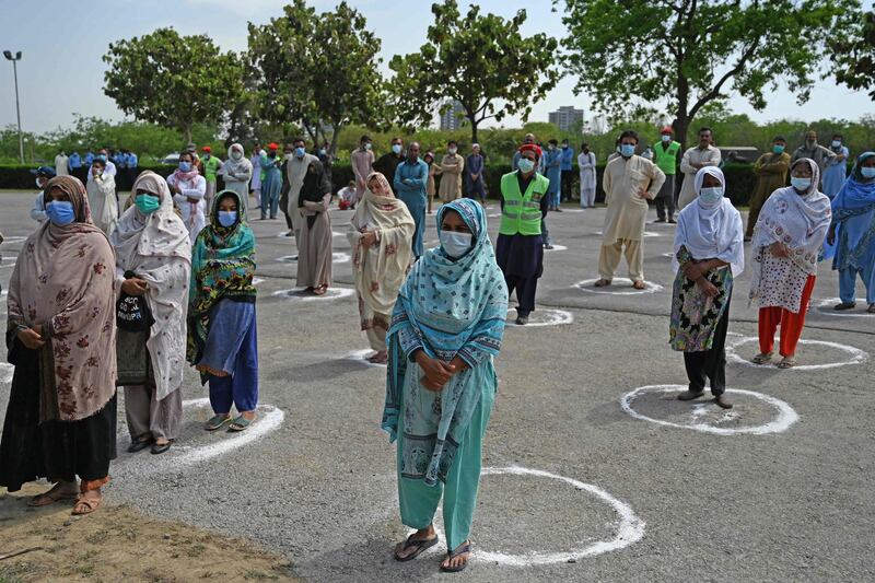People observe social distancing as they wait to receive foodstuffs from the UAE embassy ahead of Ramadan in Islamabad.