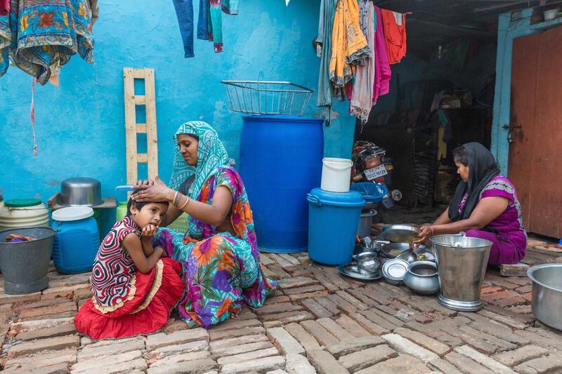 An Indian woman combs the hair of her daughter on Mother's Day as another woman washes utensils, in Allahabad, India. Rajesh Kumar Singh / AP Photo