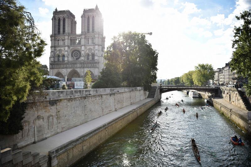 Rowers scull past Notre Dame Cathedral as they take part in La Traversee de Paris en Aviron on the Seine. AFP