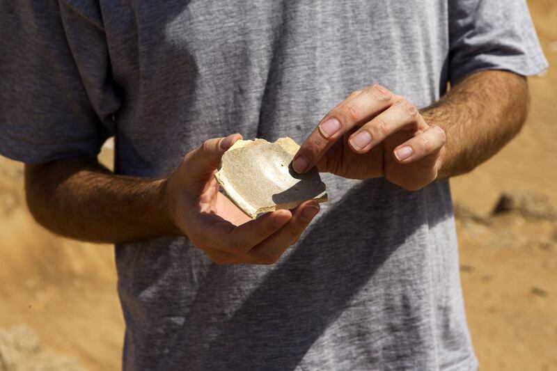 Tim Power, archaeologist and professor at Zayed University holds an estimated 1000 year old pottery shard, found on the surface during the shoot, at the site of a Oman-UAE joint archaeological project un-earthing remains of an early Islamic settlement, 9th century, which they believe represents the remains of the lost city of Tawam near the border with the UAE in Buraimi on September 12, 2015. Christopher Pike / The National