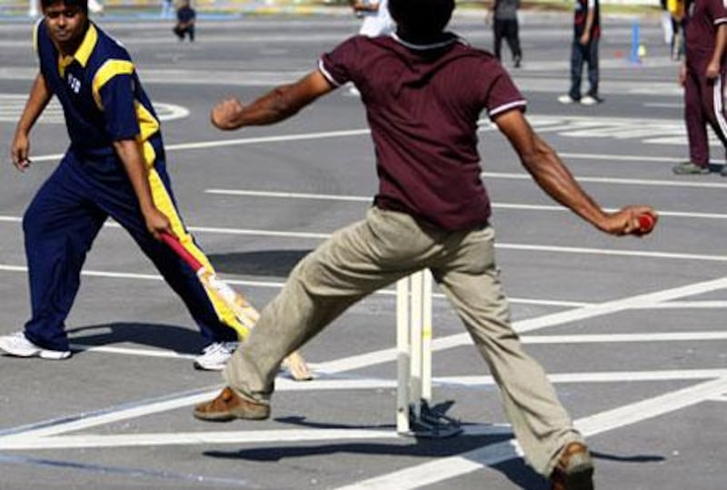Two teams play in a company cricket match held in an Abu Dhabi car park.