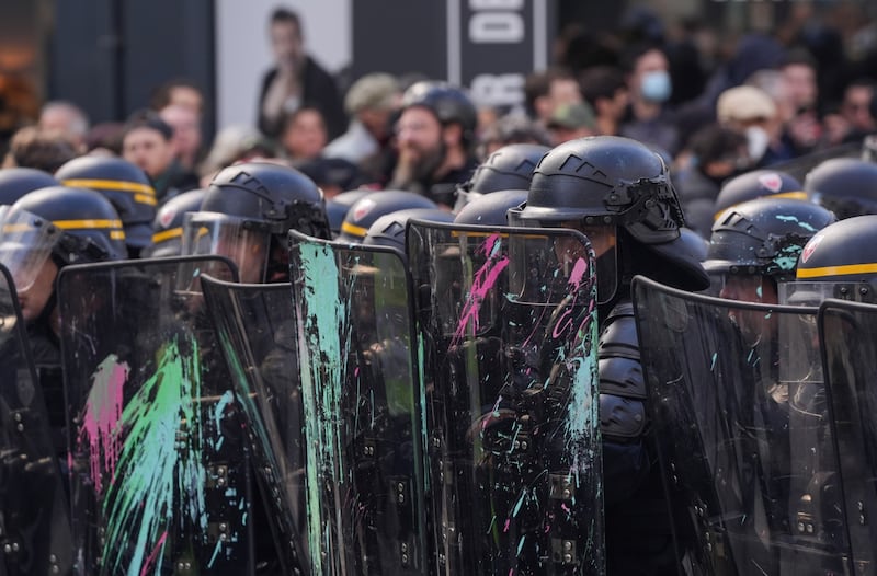 Riot police take cover from paint bombs and projectiles behind protective shields during a demonstration. Bloomberg