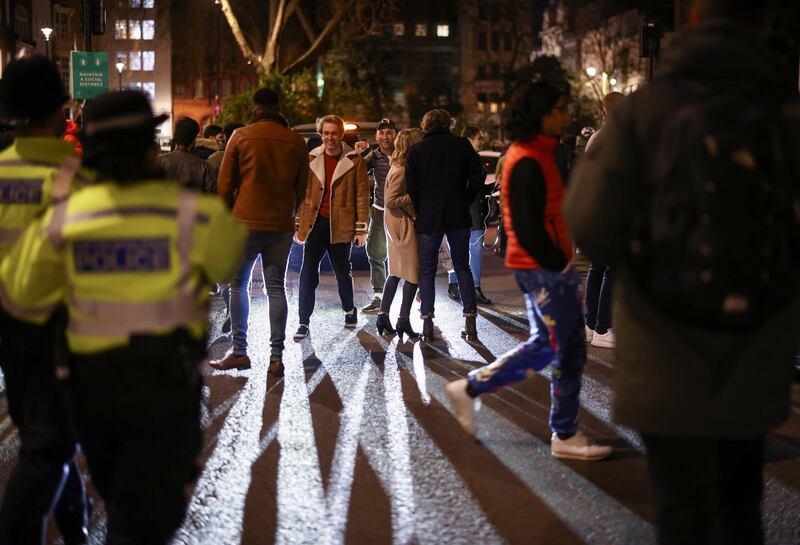 Police look on as people walk through Soho in London. Reuters