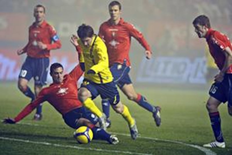 Lionel Messi, in yellow, attempts to dribble through the Osasuna defence.