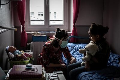 An educator wears a face mask as she speaks with a girl on April 20, 2020 in the "L'etoile du berger" institution for children in social or parental distress in La Mulatière near Lyon, during the 35th day of a strict lockdown in France aimed at curbing the spread of the COVID-19 infection caused by the novel coronavirus. (Photo by JEAN-PHILIPPE KSIAZEK / AFP)