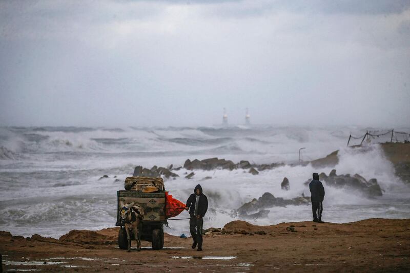 A Palestinian walks with his donkey-drawn cart loaded with collected junk along the Mediterranean seashore during stormy weather in Gaza. AFP