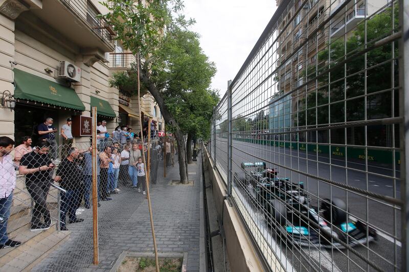 Spectators watch the race from behind a fence as Mercedes' Lewis Hamilton drives past. Reuters