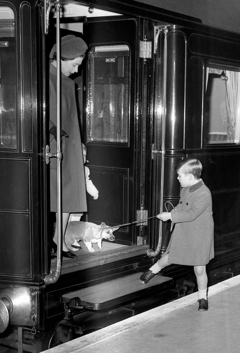 Prince Andrew attempting to help a reluctant corgi to leave the train at Liverpool Street Station, London, in 1966. AFP
