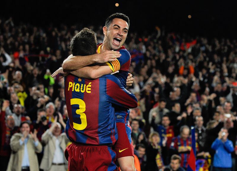 Former Barcelona midfielder Xavi, now first-team coach, celebrates with Gerard Pique after Pique scored their team's third goal during the Champions League quarter-final first leg against Shakhtar Donetsk at Camp Nou on April 6, 2011 in Barcelona, Spain. Getty Images