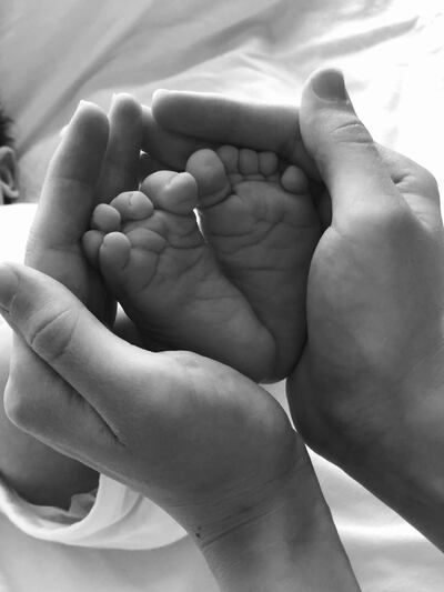 Sara cups her newborn son's feet for a staged photo. She has coronavirus when she gave birth to him at Corniche Hospital. Courtesy: Sara