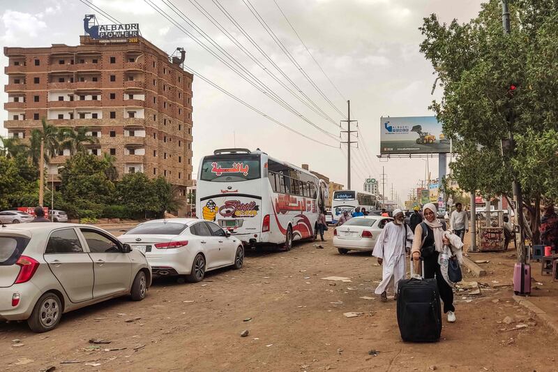 People board a bus leaving Khartoum as battles between military factions rage in the city. AFP