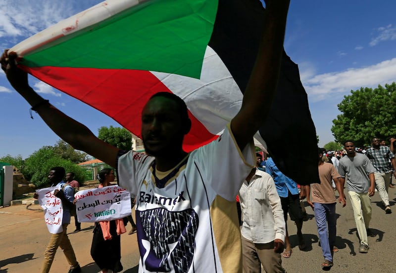 A Sudanese protester carries their national flag as they march in a demonstration to mark the anniversary of a transitional power-sharing deal with demands for quicker political reforms in Khartoum, Sudan August 17, 2020. REUTERS/Mohamed Nureldin Abdallah