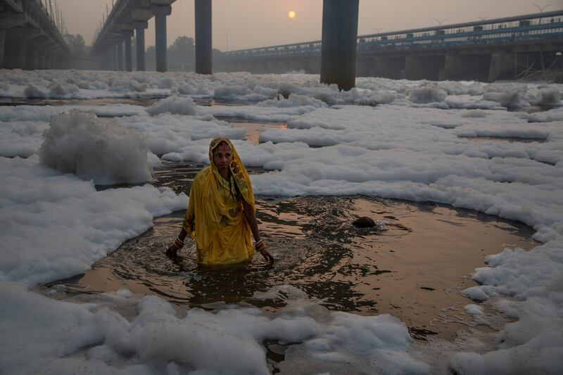A Hindu worshipper performs rituals in the River Yamuna, which is covered by chemical foam caused by industrial and domestic pollution, during the Chhath Puja festival in New Delhi, India. AP