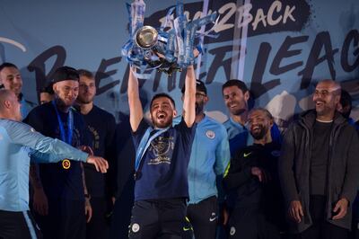 Manchester City's Portuguese midfielder Bernardo Silva (C) shows the Premier League trophy to supporters outside the Etihad Stadium in Manchester, northern England on May 12, 2019.   Manchester City held off a titanic challenge from Liverpool to become the first side in a decade to retain the Premier League on Sunday by coming from behind to beat Brighton 4-1 on Sunday. / AFP / OLI SCARFF
