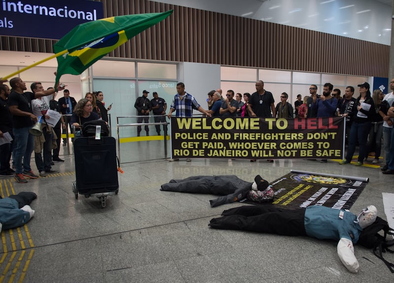 Police officers and firemen welcome passengers with a banner reading "Welcome to Hell" as they protest against the government for delay in their salary payments at Tom Jobim International Airport in Rio de Janeiro, Brazil, 4 July 4, 2016
