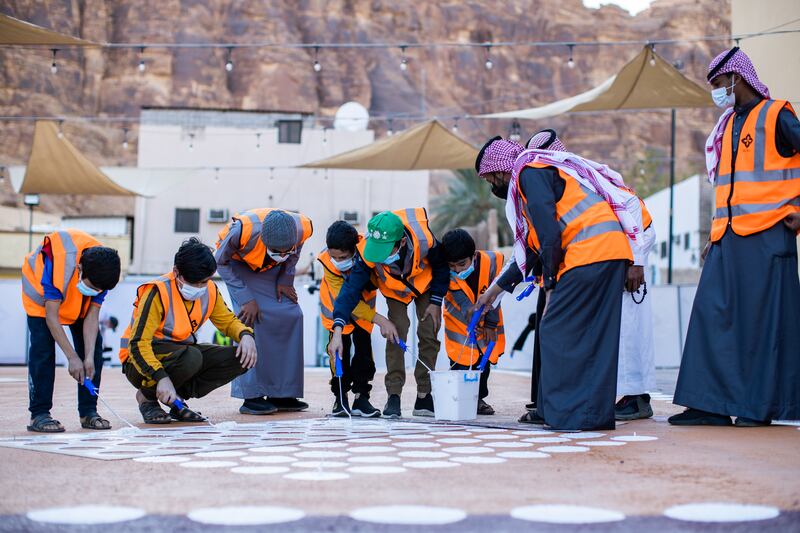 Workers preparing a market square with floor painting in AlJadidah.