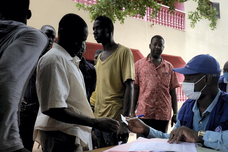 An IOM (International Organisation for Migration) agent (R) distributes an economic subsidy for migrants recently repatriated from Niger to Bamako on July 7, 2020. - After being expelled from Algeria in March 2020, where he was working for three years, Aboubacar Traore, 43, a former Imam of his village, was stuck for several months during the Covid-19 pandemic in a camp of IOM (International Organisation for Migration) in Niger and then repatriated to Bamako where he started the journey back to his home village in Mali. (Photo by MICHELE CATTANI / AFP)