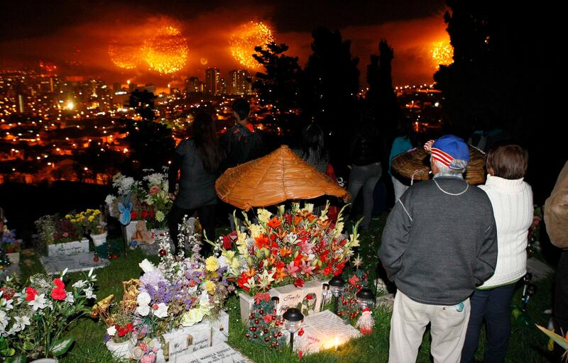 People watch a fireworks display during New Year celebrations at a cemetery in Vina del Mar city, about 121 km (75 miles) northwest of Santiago, January 1, 2012. Dozens of families gathered at the cemetery to celebrate the start of the new year alongside the graves of their loved ones, as part of a tradition which began some years ago in Vina del Mar. REUTERS/Eliseo Fernandez (CHILE - Tags: SOCIETY) *** Local Caption ***  ELF03_CHILE-_0101_11.JPG