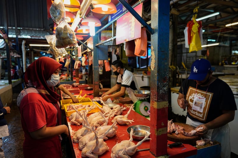 A woman wearing a face mask at a poultry stall in a wet market in Kuala Lumpur, Malaysia on the first day of Ramadan. AP Photo
